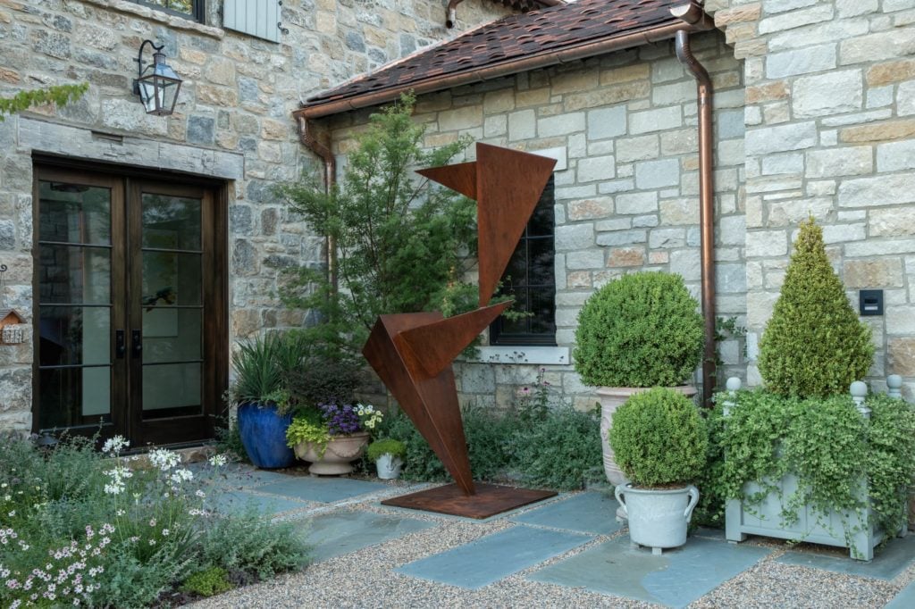 Garden sculpture in courtyard of mountain retreat with planting clusters around it