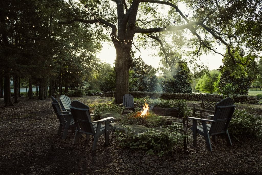 hearth in deep woods surrounded by seating looking out on luxury garden